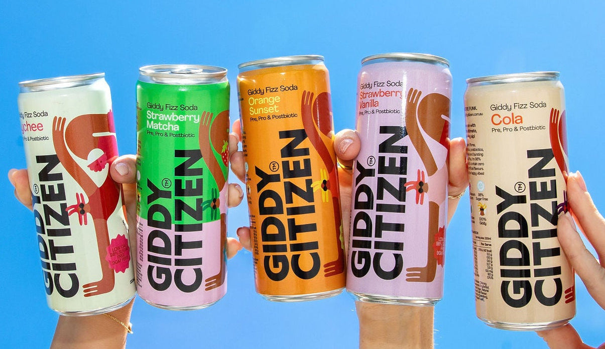 Five cans of Giddy Citizen drinks held up against a clear blue sky.